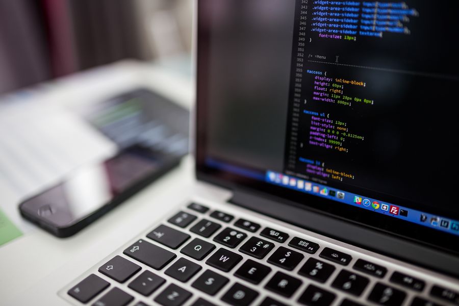 Ordinateur portable affichant du code CSS, avec un smartphone posé à côté