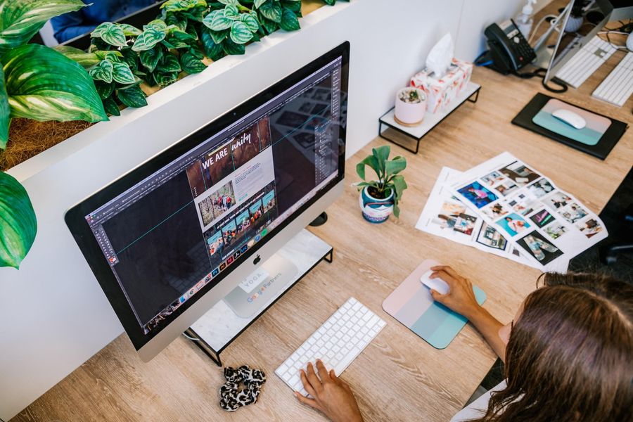 Personne travaillant sur la maquette d'un site web sur un ordinateur iMac, entourée de plantes