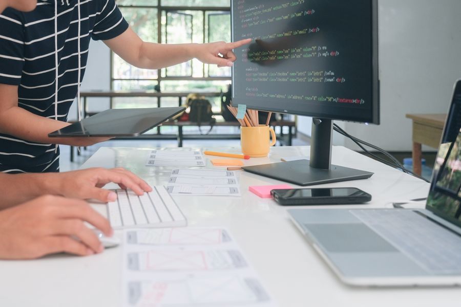 Main pointant du code HTML affiché sur un écran d'ordinateur