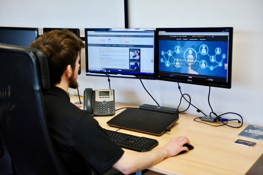Personne travaillant à un bureau avec deux écrans affichant un site web professionnel