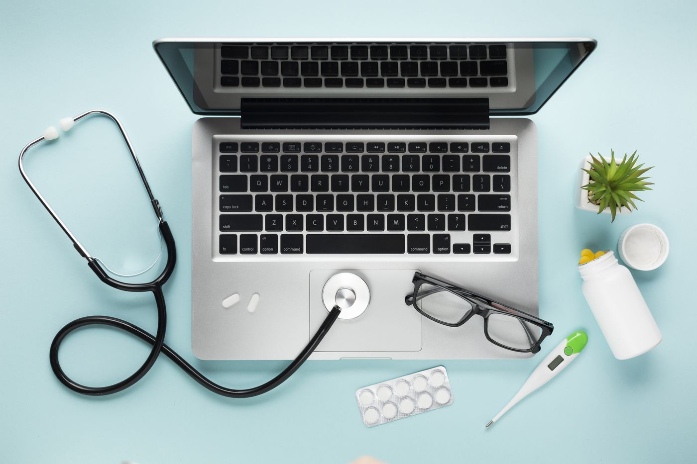 Ordinateur portable avec stethoscope, lunettes et medicaments, vue de dessus
